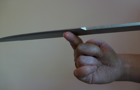 Find the balance point by moving the knife to the point where the knife does not tilt to either side.